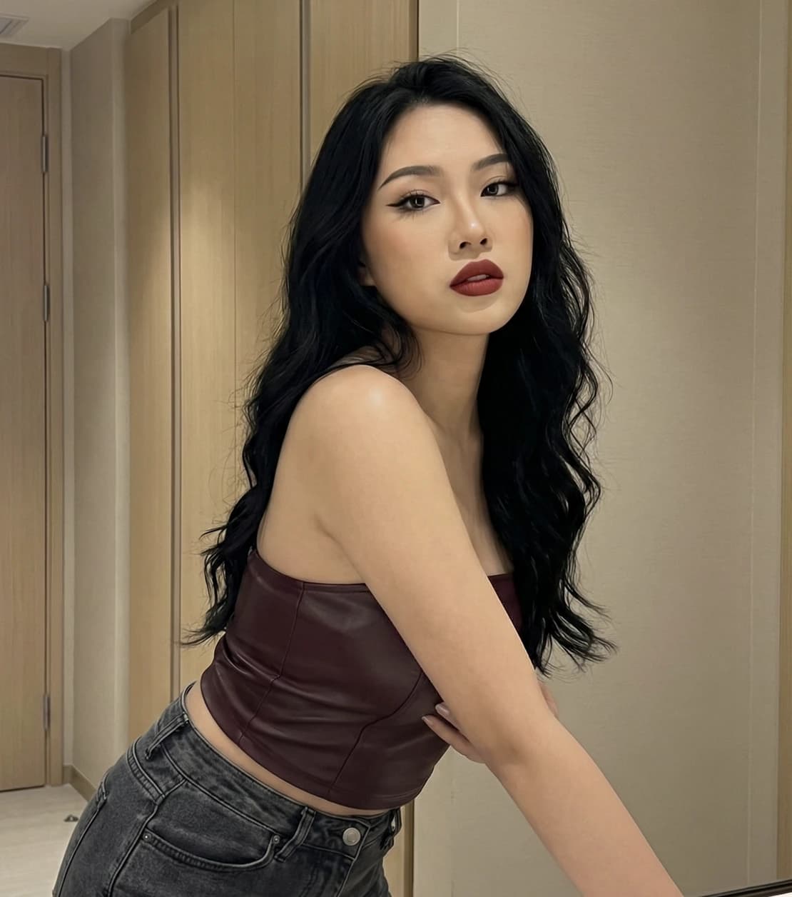 A woman with long black hair wearing a leather top