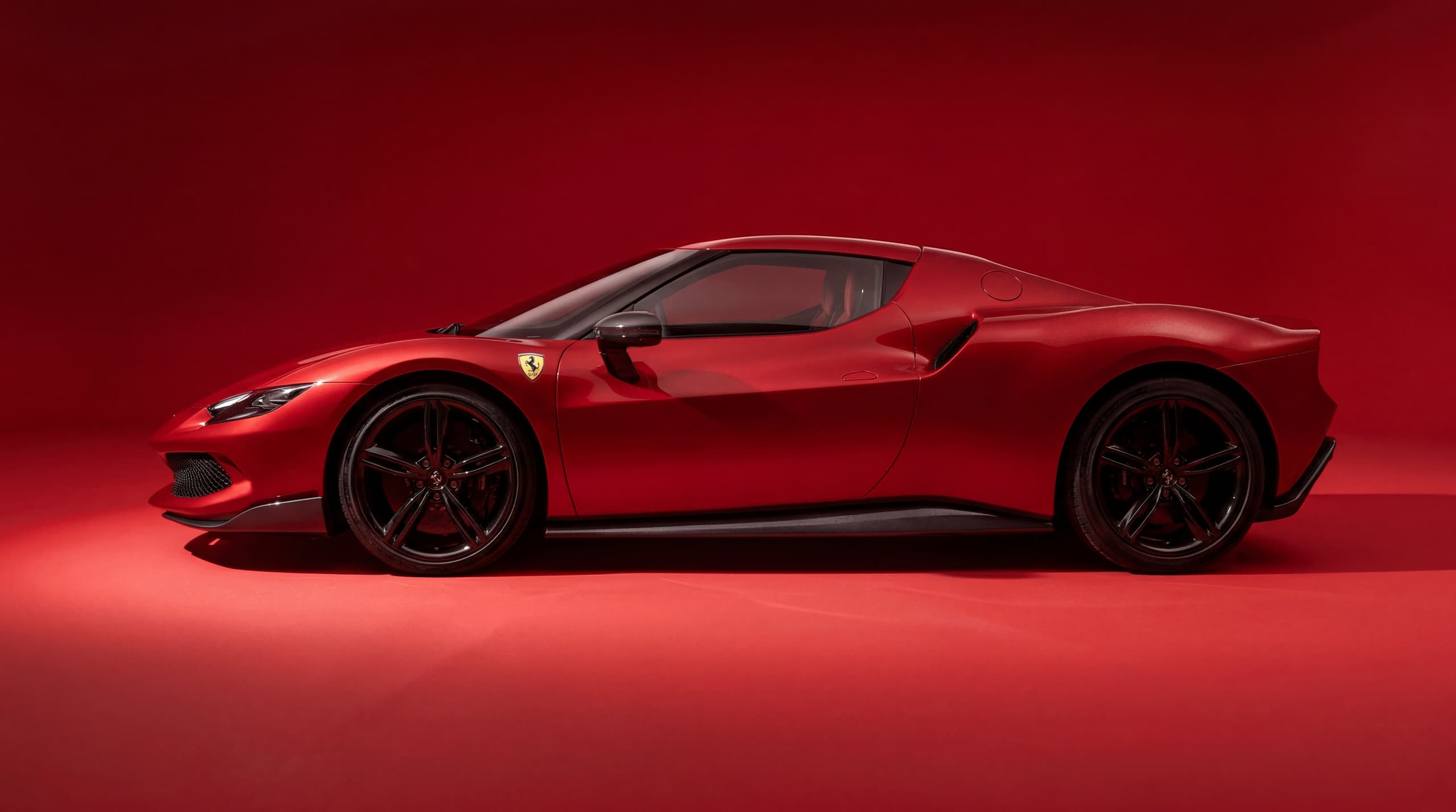 Red sports car in profile against a matching red studio backdrop